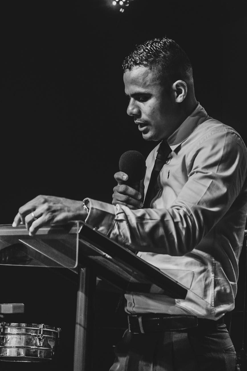 a grayscale of a man talking with a microphone